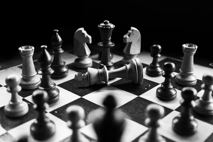 A chess board mid-game in dramatic black and white