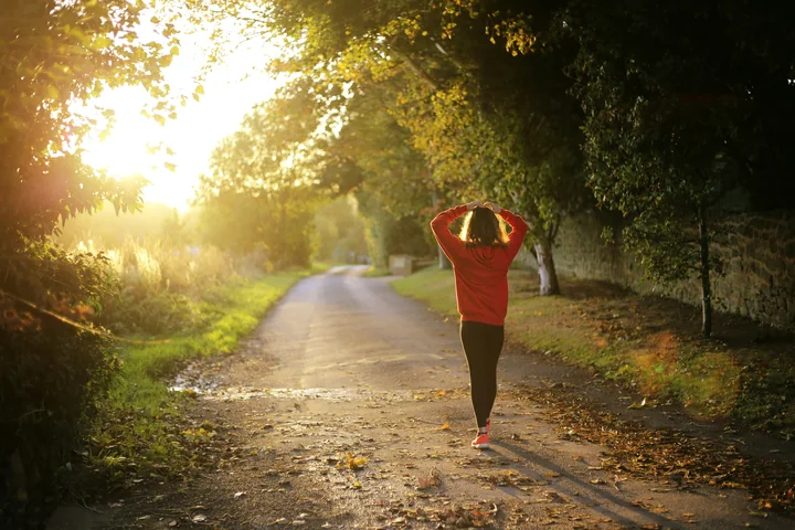 A woman walking forward down a path into golden morning light